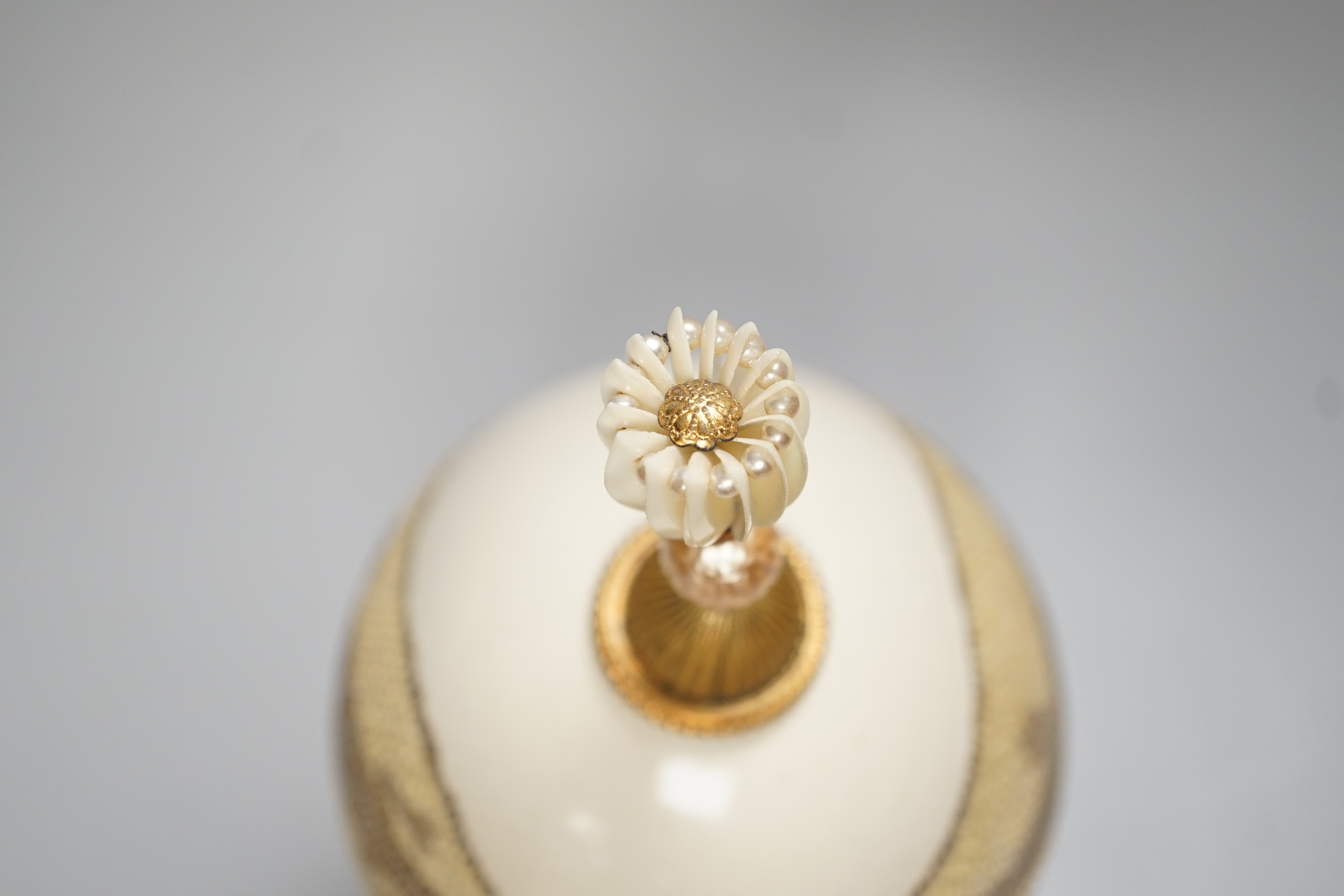 A decorated ostrich egg on gilt stand with a gilt and seed finial, 27cms high